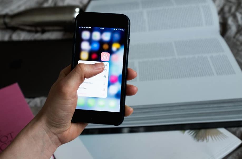 Freelance designer at a desk sending an invoice from a phone
